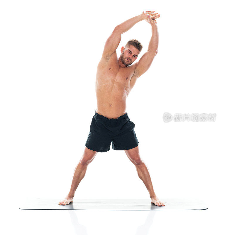 英俊的人/高个子的男性准备瑜伽/伸展/锻炼穿着短裤/瑜伽裤/慢跑裤/打底裤谁是肌肉的构建/一个性感的象征，使用锻炼垫/性感